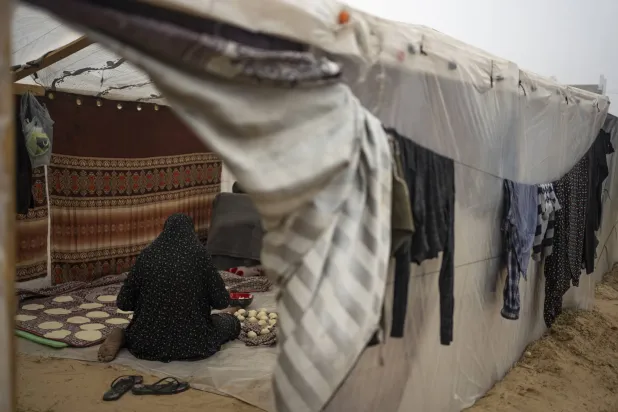 امرأة فلسطينية نزحت بسبب القصف الإسرائيلي على قطاع غزة تطبخ في مخيم الخيام المؤقت في منطقة المواصي (أ.ب)