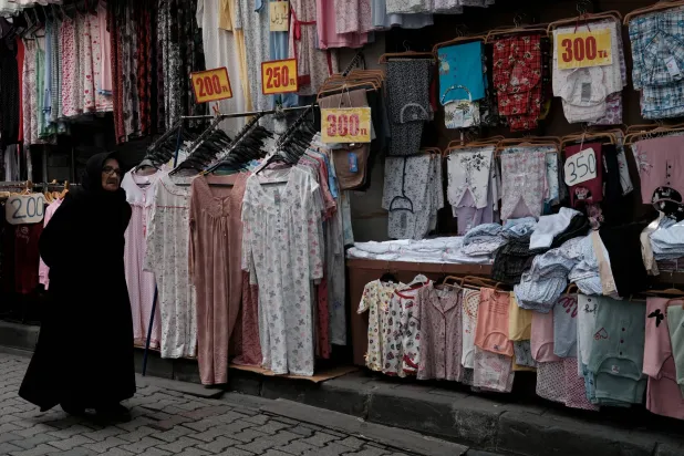 امرأة تمشي أمام متجر لبيع الملابس في منطقة تسوق شهيرة للطبقة المتوسطة بإسطنبول (رويترز)
