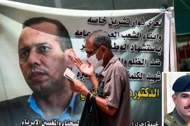أحمد الكناني الضابط الذي اغتال هشام الهاشمي - صورة أرشيفية لعراقي أمام ملصق للباحث هشام الهاشمي الذي قُتل بالرصاص في بغداد يوليو 2020 (أ.ب)