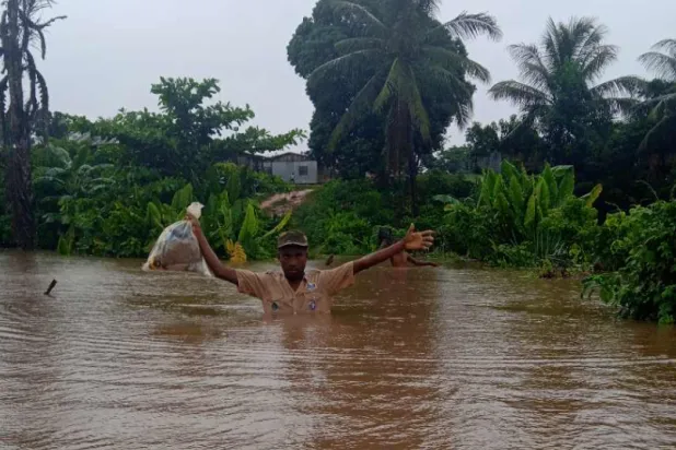 شاب يحمل حقيبة بلاستيكية في حين تصل المياه إلى صدره نتيجة الإعصار في مدغشقر (صفحة منظمة «تلي» غير الربحية عبر «فيسبوك»)
