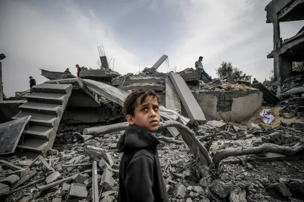 A child stands in front of the rubble of buildings destroyed by Israeli raids on the Maghazi camp in the southern Gaza Strip on Friday (AP)