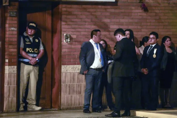 الشرطة والمدعون العامون يقفون خارج منزل الرئيسة دينا بولوراتي خلال مداهمة تهدف إلى الاستيلاء على ساعات روليكس كجزء من تحقيق أولي في الإثراء غير المشروع المزعوم في ليما (أ.ب)