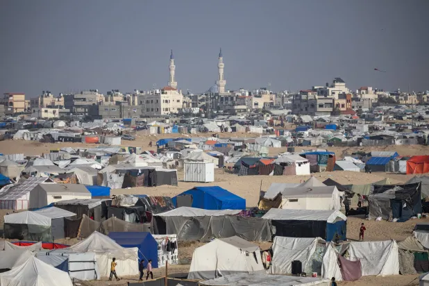 نازحون فلسطينيون فروا من منازلهم بسبب الغارات الإسرائيلية يحتمون بالقرب من الحدود مع مصر في رفح (إ.ب.أ)