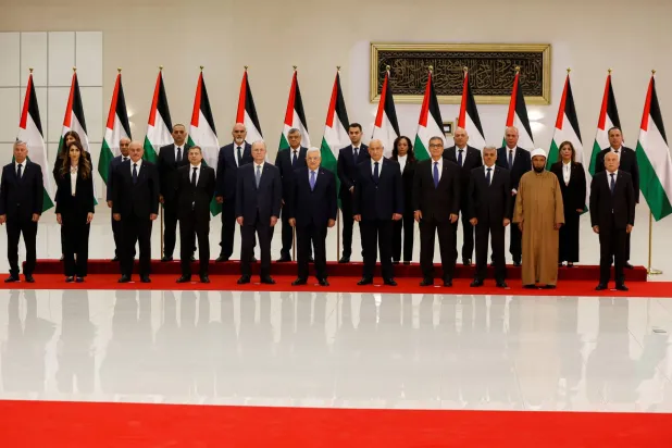 الرئيس الفلسطيني متوسطاً رئيس وأعضاء الحكومة الفلسطينية الجديدة اليوم (رويترز)