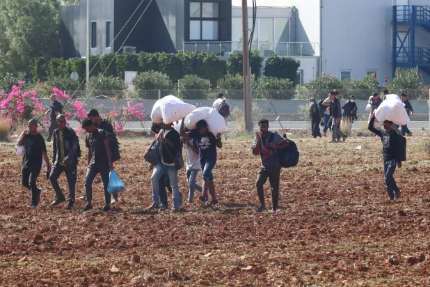 مهاجرون يغادرون مخيم بورنارا للاجئين خلال اشتباكات في كوكينوتريميثيا على مشارف نيقوسيا (رويترز)
