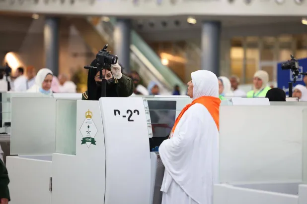 إحدى منسوبات الجوازات تقوم بعملها في إنهاء إجراءات إحدى القادمات للعمرة (الشرق الأوسط)