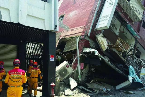 أعضاء فريق البحث والإنقاذ يعملون خارج مبنى مائل في أعقاب الزلزال الذي ضرب مدينة هوالين شرق تايوان (أ.ب)
