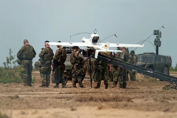 جنود بالقرب من طائرة مسيرة تستخدمها قوات ألمانية ضمن مهمة لحلف شمال الأطلسي في بابراد بليتوانيا في 7 يونيو 2022 (رويترز)