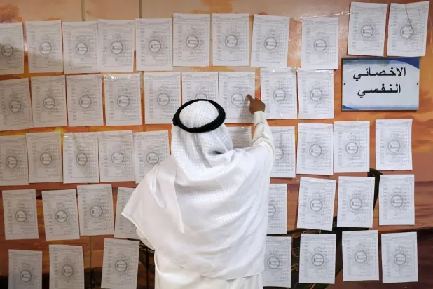A Kuwaiti man consults electoral lists before casting his vote in parliamentary elections at a polling station in Kuwait City on April 4, 2024. (AFP)