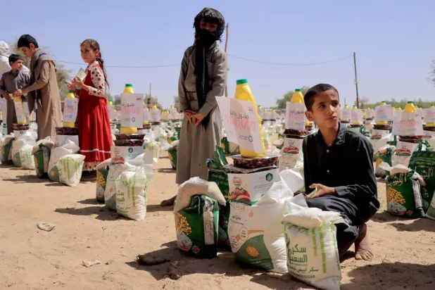 Children displaced by conflict receive food aid from a Kuwaiti charity at a displaced camp in Maarib, Yemen (AFP)