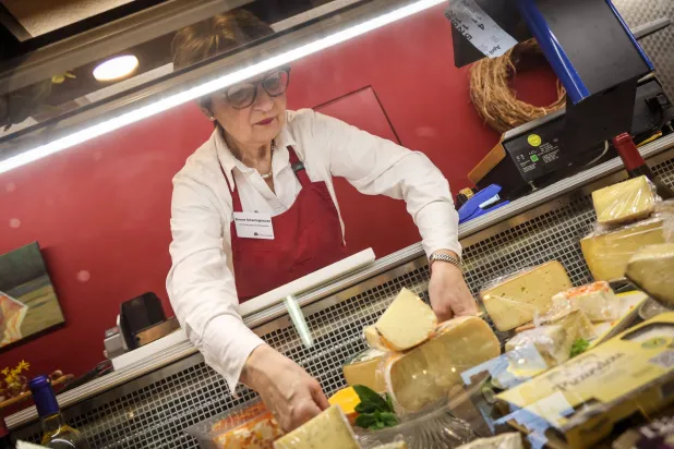 سيدة تقوم بترتيب قطع الجبن في متجرها بشمال ألمانيا (أ.ف.ب)
