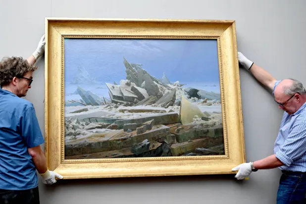 موظفان بالمتحف الوطني القديم يعلّقان لوحة «بحر الجليد» لكاسبار ديفيد فريدريش (1774 - 1840) على جدار المتحف (د.ب.أ)