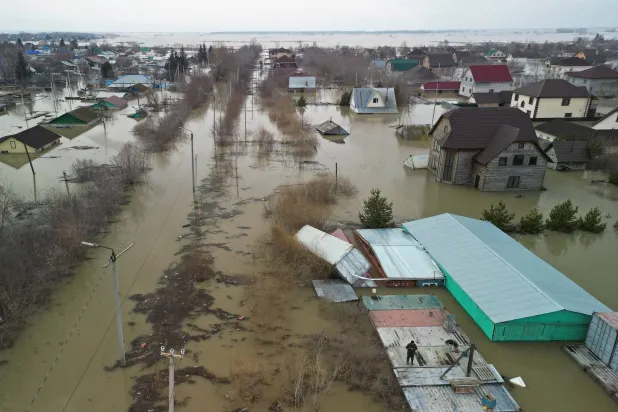 رجل يقف على قمة حاوية مع كلب أثناء الإخلاء من منطقة سكنية غمرتها الفيضانات في بتروبافل بكازاخستان (رويترز)