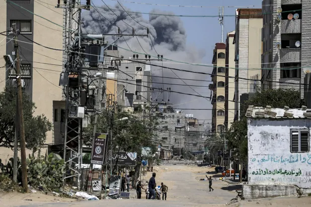 فلسطينيون يفرون من المنطقة خلال عملية عسكرية إسرائيلية في مخيم النصيرات للاجئين وسط قطاع غزة الأربعاء (إ.ب.أ)