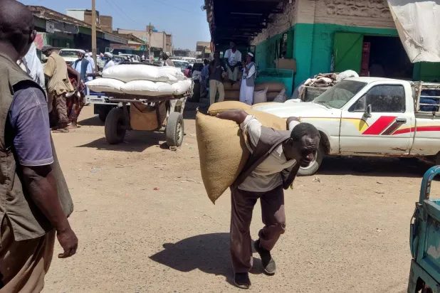 سوداني يحمل كيساً من الحبوب يوم الأربعاء في مدينة القضارف شرق السودان (أ.ف.ب)