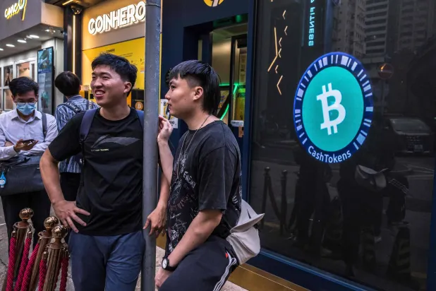 شباب يقفون بالقرب من بورصة العملات المشفرة في هونغ كونغ (أ.ف.ب)