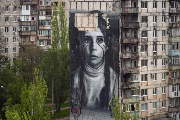 صورة التُقطت الأحد تظهر جدارية من عمل الفنان الإيطالي جوريت تظهر صورة لفتاة في مبنى سكني بماريوبول الخاضعة لسيطرة روسيا (أ.ف.ب)