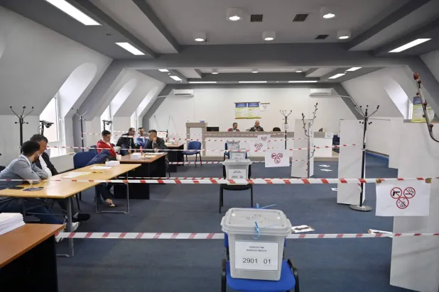 موظفو اللجنة الانتخابية يجلسون في مركز اقتراع ببلدة زفيتشان شمال كوسوفو الأحد (أ.ف.ب)