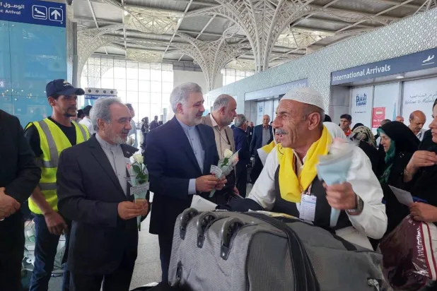 السفير الإيراني لدى السعودية علي رضا عنايتي خلال استقبال الدفعة الأولى للمعتمرين الإيرانيين بمطار المدينة المنورة (السفارة الإيرانية)