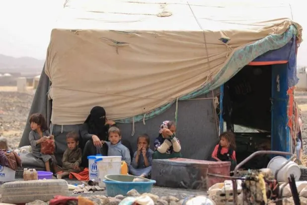 An internally displaced Yemeni family sit outside their shelter at Al-Suwaidan camp in Marib city, Yemen, June 2021 (UNHCR)
