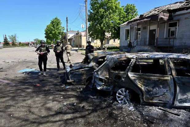 عناصر من الشرطة الأوكرانية يتفقدون سيارات مدمرة في موقع ضربة صاروخية روسية على قرية زولوتشيف بمنطقة خاركيف في 1 مايو 2024 (أ.ف.ب)