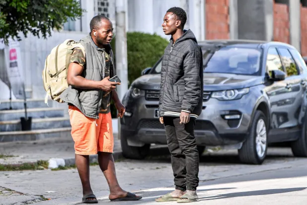 سودانيان يقفان خارج مقر منظمة الهجرة الدولية في تونس بعد إزالة خيامهما الليلة الماضية وإجبارهما على إخلائها 3 مايو 2024 (أ.ف.ب)