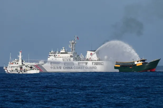 سفن خفر السواحل الصينية وهي توجه خراطيم المياه تجاه مركب تابع للجيش الفنزويلى في المياه المتنازع عليها ببحر الصين الجنوبي (أ.ف.ب)