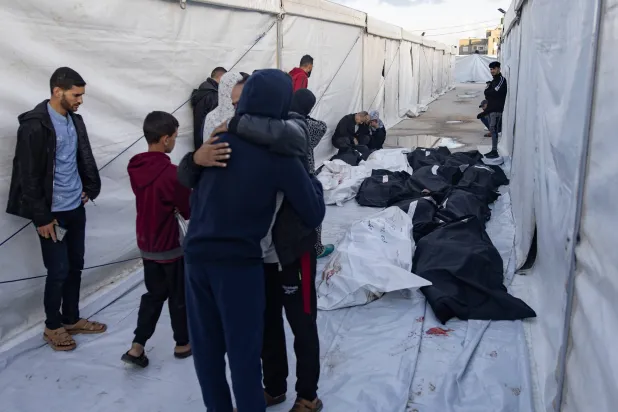 أقارب الفلسطينيين الذين قُتلوا خلال الغارات الجوية الإسرائيلية الليلية على مخيم رفح للاجئين يبكون بجوار جثثهم الملفوفة خارج مستشفى رفح الميداني في رفح جنوب قطاع غزة اليوم (إ.ب.أ)