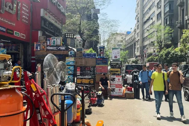 أشخاص يسيرون أمام أحد محال معدات الكهرباء الصناعية في القاهرة (رويترز)