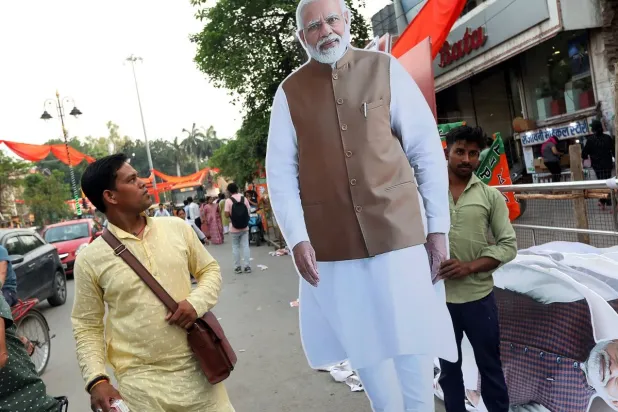 رجل يحمل مجسماً كبيراً لرئيس الوزراء الهندي ناريندرا مودي (إ.ب.أ)