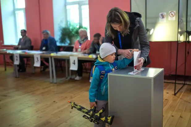 سيدة وطفلها يشاركان في الجولة الأولى من الانتخابات الرئاسية بليتوانيا (أ.ب)