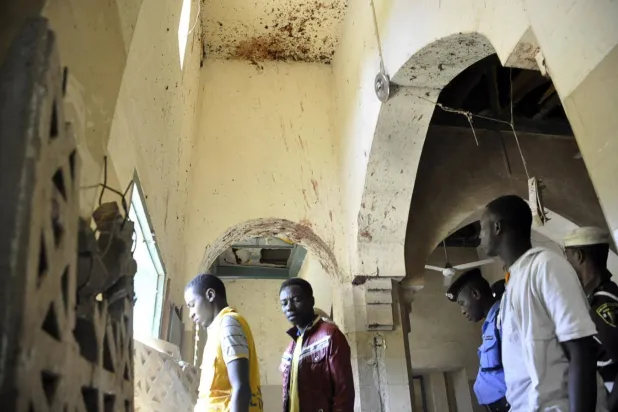 أفراد من وكالة الأمن والطوارئ يسيرون بين جدران ملطخة بالدماء أثناء التحقيق في مسجد كانو المركزي في كانو في 29 نوفمبر 2014، بعد أن فجر مسلحون ثلاث قنابل وفتحوا النار على المصلين في المسجد الرئيسي في كانو، أكبر مدن شمال نيجيريا (رويترز)