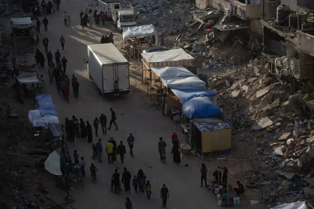 Refah'tan ayrılmak zorunda kalan Filistinliler, Han Yunus'taki bir kampta yürüyor. (EPA)