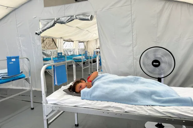 طفلة فلسطينية مصابة تستلقي على سرير أمام مستشفى ميداني تابع للصليب الأحمر جنوب غزة (رويترز)