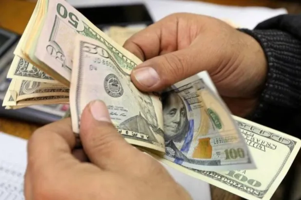 رجل يعد أوراق نقد من فئات مختلفة من الدولار الأميركي في مكتب صرافة بالقاهرة (رويترز)