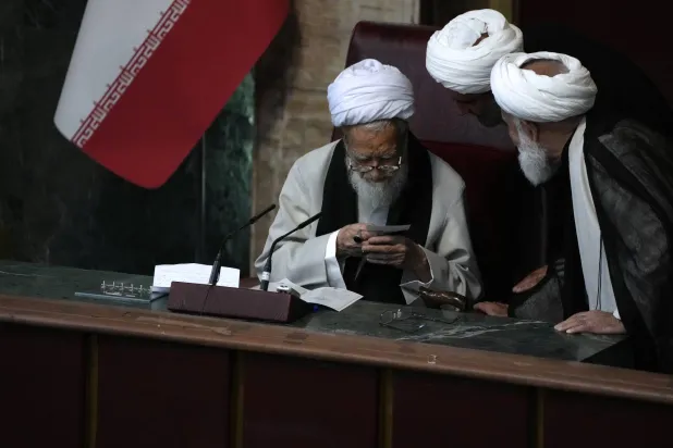 اثنان من أعضاء مجلس الخبراء ينظران إلى شاشة هاتف جوال بيد موحدي كرماني (أ.ب)