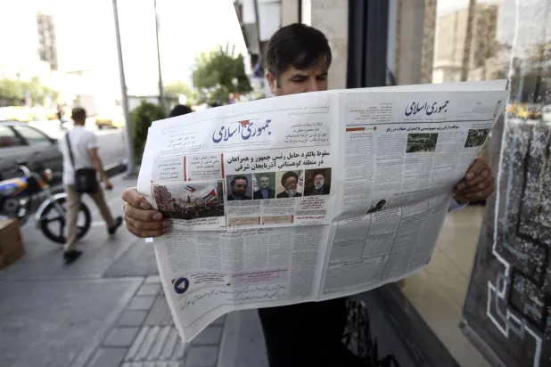 إيراني يقرأ صحيفة «جمهوري إسلامي» غداة تحطم مروحية رئيسي (إ.ب.أ)