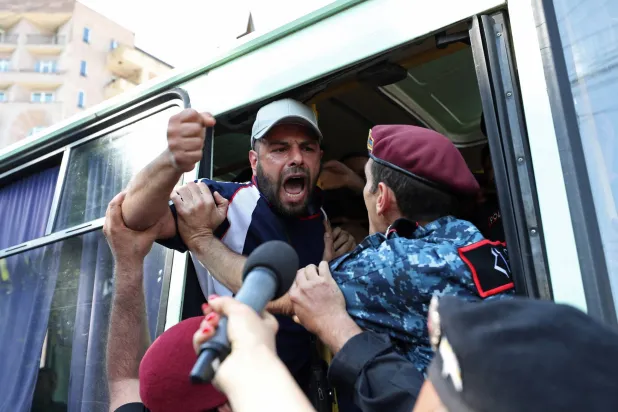 متظاهر يهتف من داخل حافلة للشرطة بعد اعتقاله في يريفان الاثنين (رويترز)