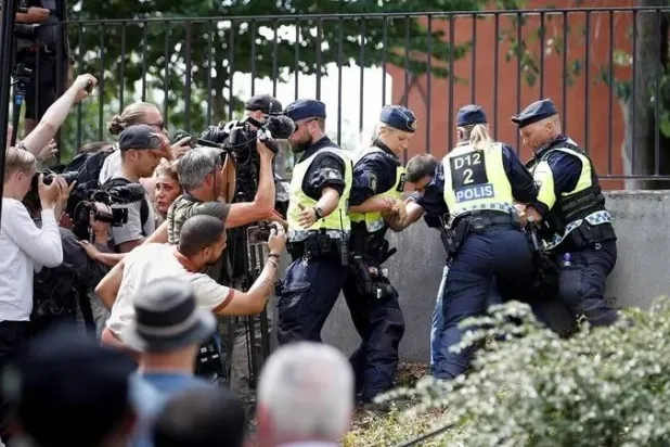 ضباط الشرطة يتدخلون بعد رد فعل الناس عندما يحرق المتظاهرون القرآن (غير موجود في الصورة) خارج المسجد المركزي في ستوكهولم في 28 يونيو 2023 (رويترز)