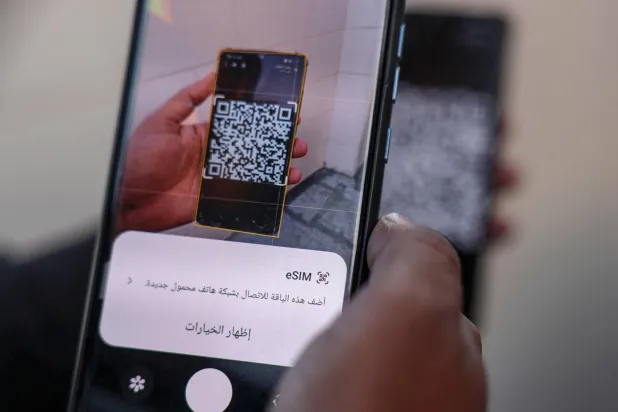 صحافي فلسطيني يحاول ربط هاتفه بشريحة إلكترونية لتفادي انقطاع الاتصالات في غزة (أ.ف.ب)