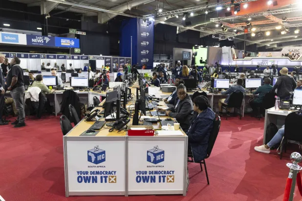 صحافيون ومسؤولون حزبيون يتابعون نتائج الانتخابات في مركز عمليات اللجنة الانتخابية المستقلة بمدينة جوهانسبرغ (أ.ف.ب)