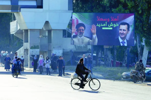 لوحة إعلانية في طريق بدمشق تحمل صورة الرئيس السوري بشار الأسد ونظيره الإيراني إبراهيم رئيسي في مايو الماضي (غيتي)