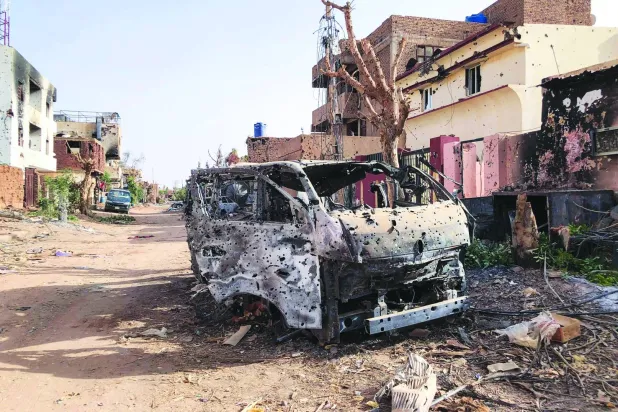 سيارة مدمرة أمام متجر في أم درمان بالسودان (أ.ف.ب)