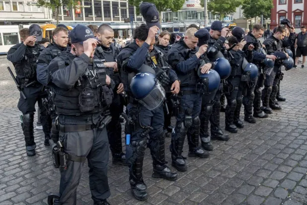 German police officers commemorate a colleague in Mannheim Germany, after learning that a police officer, who was stabbed two days ago there, has died on June 2, 2024. (AP)  