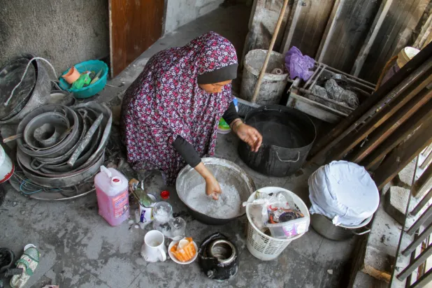 امرأة فلسطينية نازحة تغسل أدوات المطبخ في مدرسة عادت إليها مع عائلتها في مخيم جباليا للاجئين في شمال قطاع غزة في 2 يونيو 2024 (رويترز)