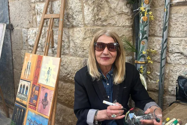 تجلس مهى العاني أمام مشغلها في الهواء الطلق وترسم (الشرق الأوسط)