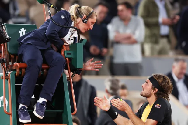 تبدو الحكمة تورت وهي تعلق الكاميرا على رأسها خلال حديثها مع اللاعب اليوناني (أ.ف.ب)