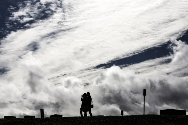 شخصان يسيران في خليج بوتاني بسيدني وسط العاصفة (أ.ف.ب)