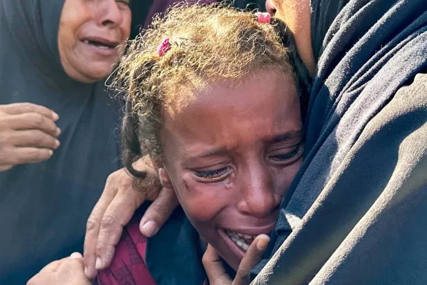 طفلة تبكي بحُرقة على ذويها الذين قُتلوا في الغارات الإسرائيلية على دير البلح (رويترز)