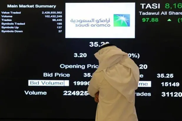 أحد المستثمرين يراقب شاشة التداول في السوق المالية عقب طرح حصة من أسهم أرامكو 2019 الرياض (رويترز)